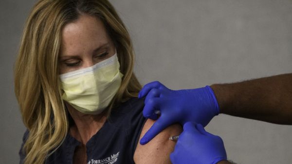 A front-line health care worker receives their first dose of the Pfizer-BioNTech Covid-19 vaccine at a vaccination site at Torrance Memorial Medical Center on December 19, 2020 in Torrance, California. The vaccine brings hope for health care workers as the Los Angeles County Department of Public Health reports over 600,000 positive COVID-19 cases in the county. Patrick T. Fallon / AFP