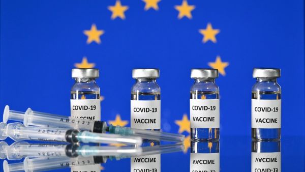 This illustration photo taken on November 17, 2020 shows vials with Covid-19 Vaccine stickers attached, and syringes, with a flag of the European Union. The EU's drug regulator authorised the Pfizer-BioNTech coronavirus vaccine on December 21, 2020, and said there was no evidence it would not work against a new strain found mainly in Britain. JUSTIN TALLIS / AFP