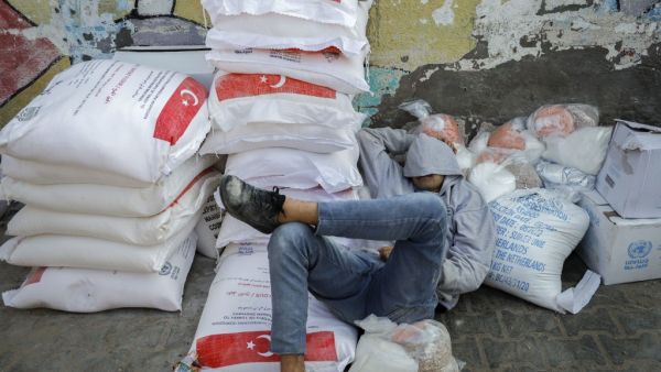 A worker rests amid food rations outside an aid distribution center run by the United Nations Relief and Works Agency (UNRWA) at the al-Shati camp for Palestinian refugees in Gaza City on December 12, 2020. Mohammed ABED / AFP