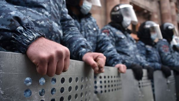 Law enforcement officers watch opposition supporters during a rally to demand the resignation of Prime Minister Nikol Pashinyan over a controversial peace deal with Azerbaijan that ended six weeks of war over the disputed region of Nagorno-Karabakh, in Yerevan on December 22, 2020. Under the deal, Armenia agreed to cede three districts to Baku in addition four others Azerbaijani forces had won back during the fighting that had been controlled by Armenian separatists since the 1990s. Karen MINASYAN / AFP