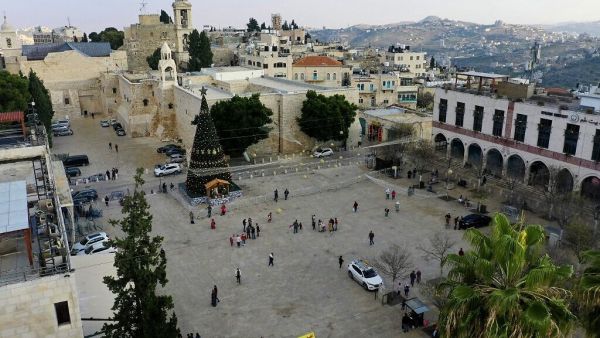 Locals visiting the Christmas tree in front of the Church of the Nativity, in the West Bank city of Bethlehem, December 22, 2020. (HAZEM BADER / AFP)