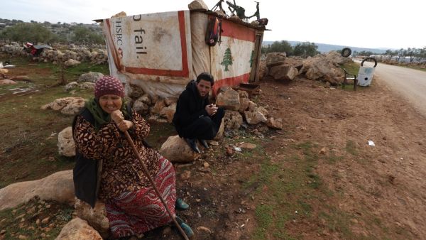 Displaced Syrian who gave his first name as Mahmud sits outside his makeshift tyre repair shop which he covered with a Lebanese flag following Beirut's massive port blast last August, in the village of Kafr Uruq in the north of Syria's rebel-held Idlib province on December 28, 2020. Mahmud kept the flag on his shack despite his disappointment with a dispute that led a group of Lebanese nationals to set fire to an informal Syrian refugee settlement in northern Lebanon on the weekend. Lebanon's army said on D