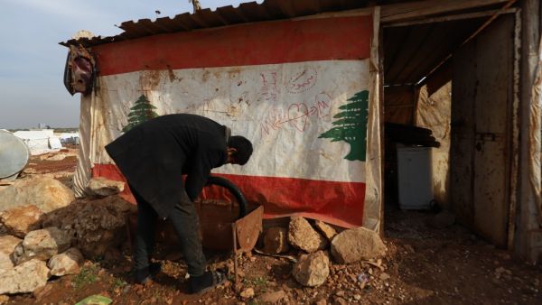 Displaced Syrian who gave his first name as Mahmud works outside his makeshift tyre repair shop which he covered with a Lebanese flag following Beirut's massive port blast last August, in the village of Kafr Uruq in the north of Syria's rebel-held Idlib province on December 28, 2020. Mahmud kept the flag on his shack despite his disappointment with a dispute that led a group of Lebanese nationals to set fire to an informal Syrian refugee settlement in northern Lebanon on the weekend. Lebanon's army said on 