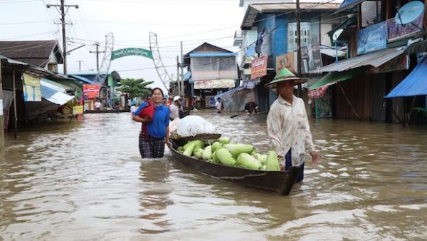 Residents use a boat to transport goods through floodwaters on a street in Hpa-an, the capital of Karen state, on Friday. (AFP Photo)