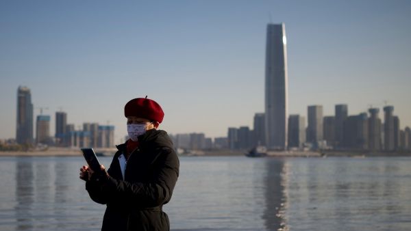 A woman uses her mobile phone along the banks of the Yangtze River on New Year's Eve day in Wuhan in China’s central Hubei province on December 31, 2020. Noel Celis / AFP