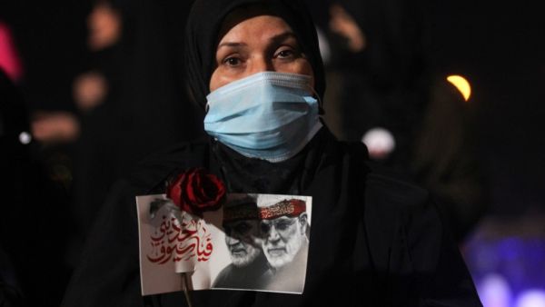 An Iraqi woman carries a portrait of late Iraqi commander Abu Mahdi al-Muhandis and Iranian commander Qasem Soleimani at Baghdad Airport, in Baghdad on January 2, 2021, at the site of their killing. On January 3, 2021, Iraq will mark the first anniversary of the killing of Iran's top military commander Qasem Soleimani in a drone strike at Baghdad International Airport that was authorized by US President Trump. AFP