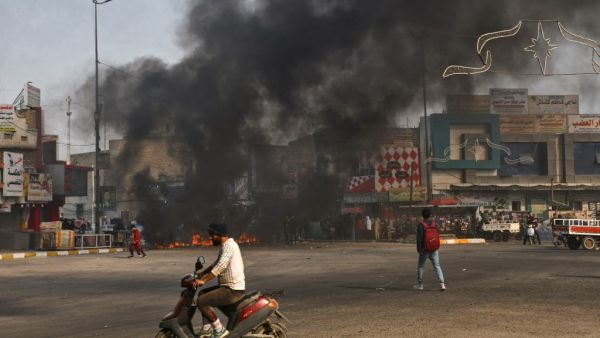 Iraqi protesters are pictured next to burning tyres during clashes with police during anti-government demonstrations in the city of Nasiriyah in the Dhi Qar province in southern Iraq on January 10, 2021. AFP