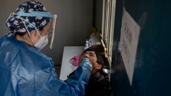 A woman (R) gets a nucleic acid test at a testing booth outside the Red Cross hospital in Wuhan on January 11, 2021, as the city marks the first anniversary of when China confirmed its first death from the COVID-19 coronavirus. NICOLAS ASFOURI / AFP A woman (R) gets a nucleic acid test at a testing booth outside the Red Cross hospital in Wuhan on January 11, 2021, as the city marks the first anniversary of when China confirmed its first death from the COVID-19 coronavirus. NICOLAS ASFOURI / AFP