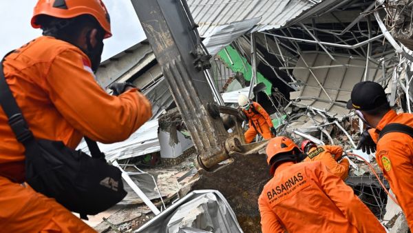 Rescuers search for survivors at the site of a collapsed building in Mamuju on January 16, 2021, a day after a 6.2-magnitude earthquake rocked Indonesia's Sulawesi island. Hariandi Hafid / AFP
