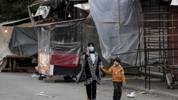 A mask-clad woman and boy walk past shuttered shops and stalls in Souk Sabra in the southern suburbs of the Lebanon's capital Beirut on January 16, 2021, despite a national total lockdown as a measure against the COVID-19 coronavirus pandemic. ANWAR AMRO / AFP