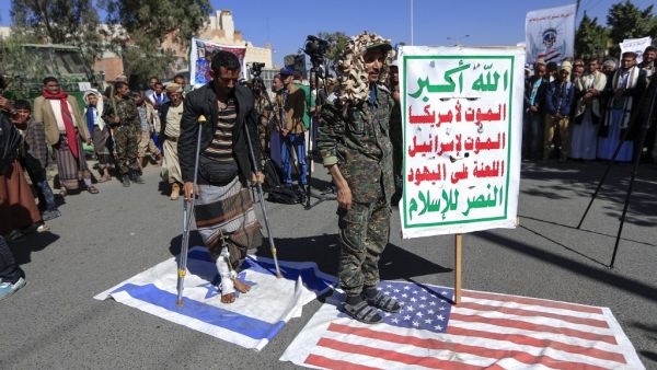 Supporters of Yemen's Huthi movement tread on US ans Israeli flags during a demonstration in front of the closed US embassy in the capital Sanaa on January 18, 2021, to reject the outgoing US administration's decision to designate the Huthis a "foreign terrorist organisation". Impoverished Yemen is mired in a devastating conflict between Iran-backed Huthi rebels and government forces backed by Saudi Arabia that has left tens of thousands dead and sparked a dire humanitarian crisis. Mohammed HUWAIS / AFP