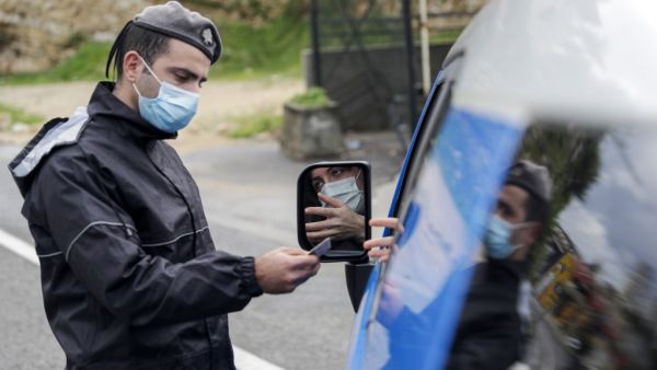 A member of the Lebanese security forces checks a citizen's documents at a COVID-19 checkpoint near the coastal town of Safra on the Tripoli-Beirut main highway on January 19, 2021, as Lebanon enters a second week under lockdown aimed at preventing the country's creaking healthcare system from collapsing. JOSEPH EID / AFP