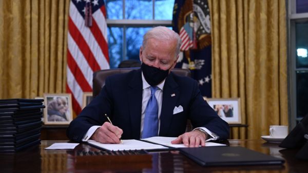 US President Joe Biden sits in the Oval Office as he signs a series of orders at the White House in Washington, DC, after being sworn in at the US Capitol on January 20, 2021. US President Joe Biden signed a raft of executive orders to launch his administration, including a decision to rejoin the Paris climate accord. The orders were aimed at reversing decisions by his predecessor, reversing the process of leaving the World Health Organization, ending the ban on entries from mostly Muslim-majority countries