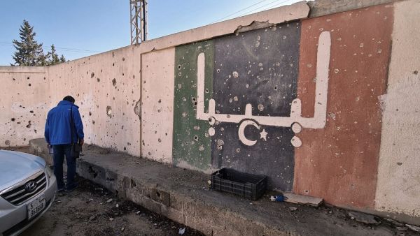 In this file photo taken on November 19, 2020, a Libyan stands in front of a school, which was damaged during fighting between rival factions, in the capital Tripoli's suburb of Ain Zara. The writing on the wall reads "Libya" in Arabic. Foreign forces ignored a deadline to pull out of Libya as scheduled Saturday under a UN-backed ceasefire deal, highlighting the fragility of peace efforts after a decade of conflict. Mahmud TURKIA / AFP