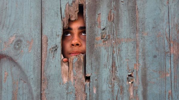 A Palestinian girl peeps from a hole at her house's gate in Beit Hanun in the northern Gaza Strip on January 25, 2021. Mohammed ABED / AFP