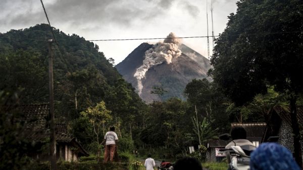 People look up at Mount Merapi, Indonesia's most active volcano, as it spews rocks and ash out for another day in Yogyakarta on January 27, 2021. Agung Supriyanto / AFP