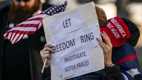  A supporter of President Donald Trump holds a MAGA hat and sign reading "Let freedom ring, investigate voter fraud" as conservative demonstrators gather at the Washington State Capitol on January 10, 2021 in Olympia, Washington. David Ryder / GETTY IMAGES NORTH AMERICA / Getty Images via AFP