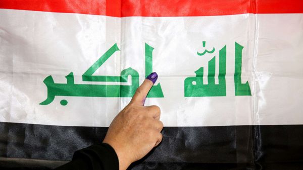 An Iraqi woman voter her ink-stained index finger before a national flag after having cast her vote in the first parliamentary election in Baghdad, May 12, 2018. (AFP)