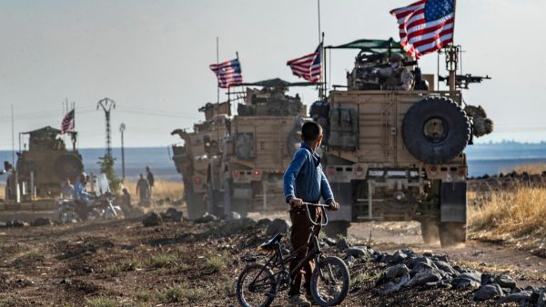  A Syrian boy on a bicycle watched a convoy of US armored vehicles drive away on a dirt road in northeastern Syria. Delil Souleiman (AFP via Getty Image File Photo)