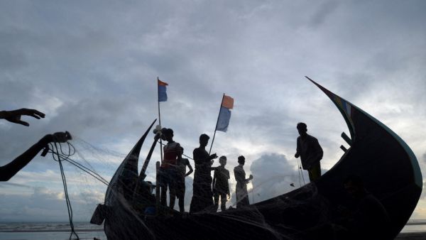 This photograph taken on August 23, 2020 shows fishermen standing next to a fishing boat that is often used to transport Rohingya refugees to bigger trawlers, anchored off the coast in Cox's Bazar. Munir UZ ZAMAN / AFP 81 Rohingya Refugees adrift in the seat for two weeks