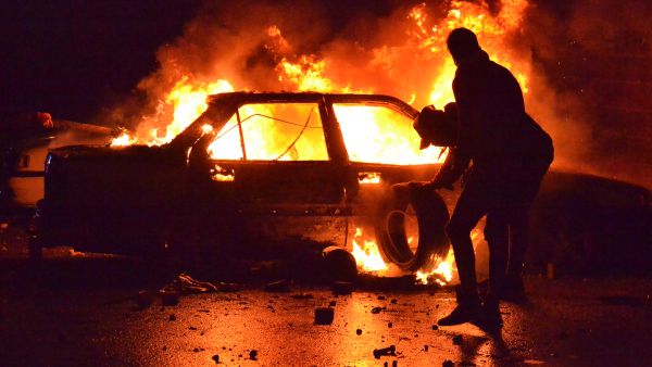 Lebanese protesters burn a vehicle in the northern port city of Tripoli. [Fathi al-Masri/AFP]