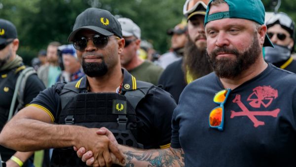 In this file photo taken on August 17, 2019 leader of the Proud Boys Enrique Tarrio (L) and rally organizer Joe Biggs (R) congratulate each other as they return to the march starting-point over the Hawthorn Bridge as "The End Domestic Terrorism" rally at Tom McCall Waterfront Park concludes in Portland, Oregon. John Rudoff / AFP