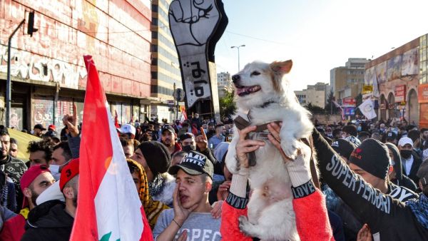 An anti-government protester holds a dog up in the air next to others chanting slogans during a demonstration in the centre of Lebanon's impoverished northern port city of Tripoli on January 31, 2021. Fathi AL-MASRI / AFP