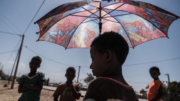 An Eritrean refugee child stands under an umbrella at Mai Aini Refugee camp, in Ethiopia, on January 30, 2021. Eritrean refugees in Ethiopia fear their suffering may not be over, as Prime Minister Abiy Ahmed strains to end a brutal conflict in the northern region of Tigray that has rendered them uniquely vulnerable. Nearly 100,000 refugees from Eritrea, an oppressive, authoritarian nation bordering Ethiopia to the north, were registered in four camps in Tigray when fighting erupted in November between Abiy'