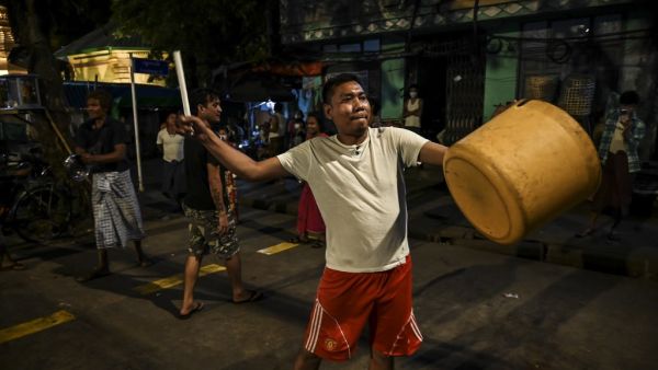A man hits a plastic container to make noise after calls for protest went out on social media in Yangon on February 3, 2021, as Myanmar's ousted leader Aung San Suu Kyi was formally charged on Wednesday two days after she was detained in a military coup. STR / AFP