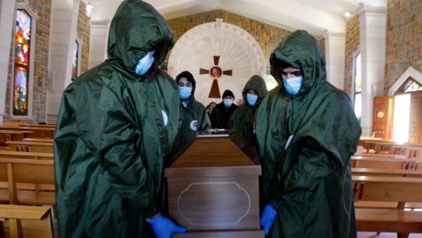 Members of Lebanon's Shiite Hezbollah movement's Islamic health unit, transport the coffin of a Lebanese Christian woman who died of the COVID-19 disease, out of a church to be inhumated in a nearby cemetary, near the southern Lebanese town of Bint Jbeil, on February 5, 2021.  Mahmoud ZAYYAT / AFP