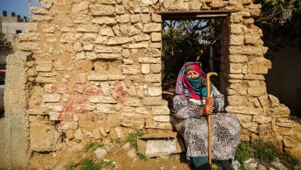 An elderly Palestinian woman sits by a wall of a demolished building near her house in Gaza City on February 6, 2021. Mohammed ABED / AFP
