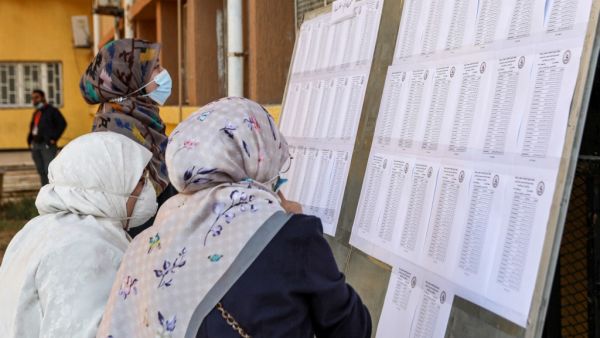 A mask-clad voter checks the electoral lists upon arriving to vote during an election for the Tripoli Municipal Council, in Libya's capital on February 6, 2021. Mahmud TURKIA / AFP