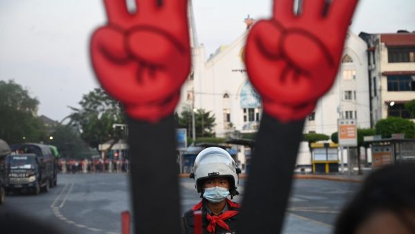 A policeman looks on next to a cut-out of the three finger salute during a demonstration against the military coup in Yangon on February 7, 2021. STR / AFP