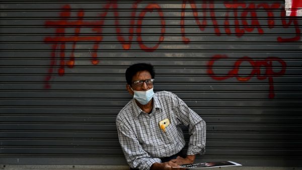 A protester sits in front a graffiti during a demonstration against the military coup in Yangon on February 9, 2021. Ye Aung THU / AFP