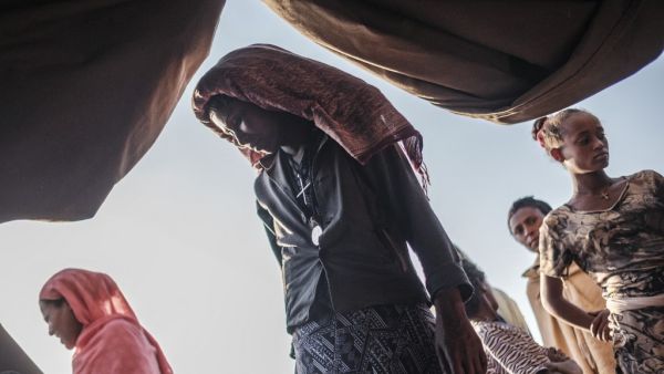 Internally Displaced People (IDP), fleeing from violence in the Metekel zone in Western Ethiopia, gather outside a tent where clothes are being distributed at a camp in Chagni, Ethiopia, on January 27, 2021. Inter-ethnic violence in Ethiopia's west -- concentrated in a lowland area known as Metekel -- predates a brutal three-month-old conflict farther north pitting Prime Minister Abiy Ahmed's government against the former ruling party of the Tigray region.  EDUARDO SOTERAS / AFP