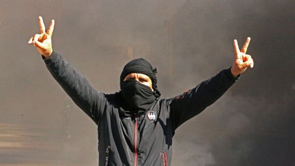 A Tunisian man flashes the V for victory sign as youths burn tires and block roads in the southern city of Tataouine, on February 12, 2021, to protest against the government's failure to keep its promise to provide jobs and investments.  FATHI NASRI / AFP