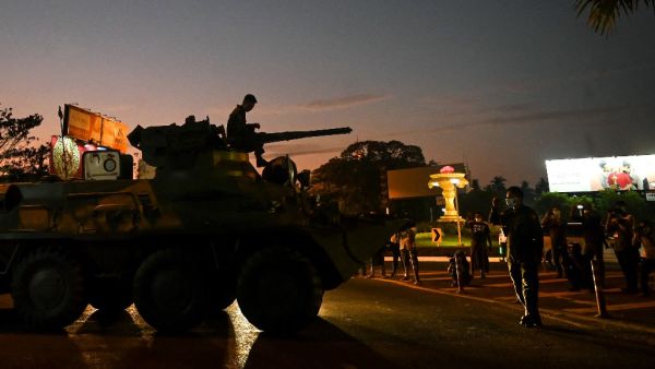 People gather around an armoured vehicle maneuvering on a city street, following days of mass protests against the military coup, in Yangon on February 14, 2021. SAI AUNG MAIN / AFP
