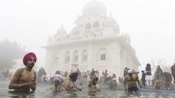 Sikh devotees take a holy dip in the Sarovar (water tank) during Basant Panchami celebrations at the Sikh Shrine Gurudwara Chheharta Sahib on the outskirts of Amritsar on February 16, 2021. NARINDER NANU / AFP