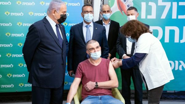 Israeli Prime Minister Netanyahu (L) stands by the 4,000,000th person to be vaccinated at Leumit Health Care Services vaccination facility in Jerusalem on February 16, 2021. Israel's largest healthcare provider said a study of more than half a million fully vaccinated Israelis indicated the Pfizer/BioNTech jab gave 94 percent protection against Covid-19. Alex KOLOMIENSKY / POOL / AFP