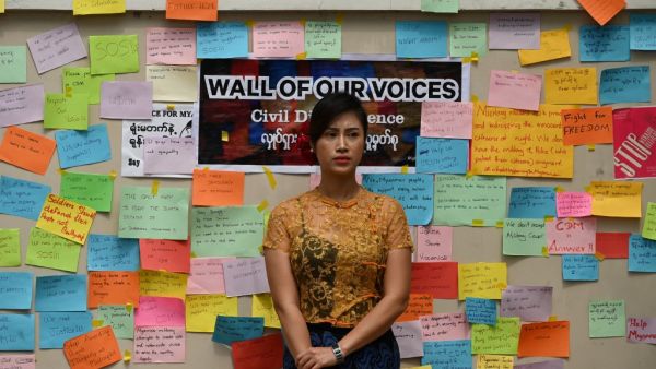 A woman stands in front of a wall with protest messages during a demonstration against the military coup in Yangon on February 18, 2021. Sai Aung Main / AFP