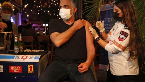 A health worker administers the COVID-19 vaccine to an Israeli at a bar in the coastal city of Tel Aviv on February 18, 2021. GIL COHEN-MAGEN / AFP