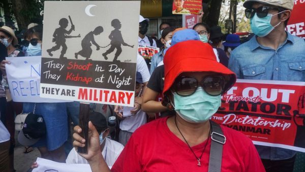 Protesters hold signs as they take part in a demonstration against the military coup in front of the Indonesian embassy in Yangon on February 23, 2021. Sai Aung Main / AFP