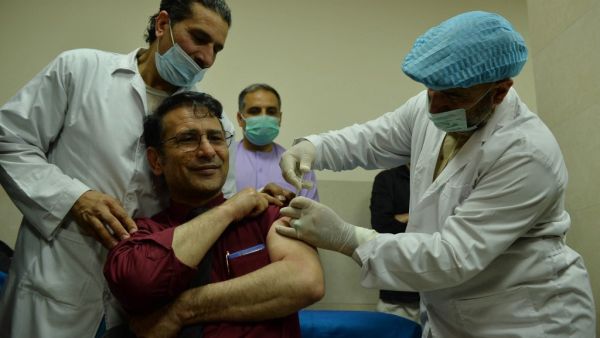 A medical worker (R) administers a dose of a Covid-19 coronavirus vaccine to a colleague at a hospital in Herat on February 24, 2021. Hoshang Hashimi / AFP