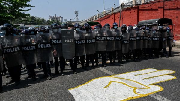 Riot police stand guard on a road, behind a street mural of the protesters' three finger salute, after a clash between pro-junta supporters and anti-military coup protesters in Yangon on February 25, 2021. Ye Aung Thu / AFP Riot police stand guard on a road, behind a street mural of the protesters' three finger salute, after a clash between pro-junta supporters and anti-military coup protesters in Yangon on February 25, 2021. Ye Aung Thu / AFP