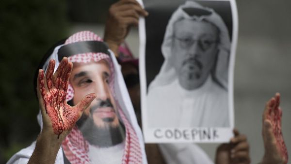 In this file photo taken on October 10, 2018, a demonstrator dressed as Saudi Arabian Crown Prince Mohammed bin Salman (C) with blood on his hands protests outside the Saudi Embassy in Washington, DC, demanding justice for missing Saudi journalist Jamal Khashoggi. The US director of national intelligence is expected to release a damning report on February 26, 2021, that fingers Saudi Crown Prince Mohammed bin Salman for the brutal murder and dismemberment of dissident journalist Jamal Khashoggi in October 2