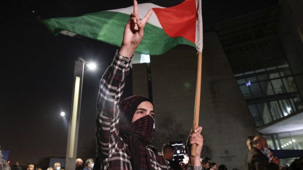 A demonstrator raises a hand with the victory gesture while holding a Palestinian flag outside the Haifa District Court in Israel's northern Mediterranean coastal city on February 27, 2021, during a protest by Arab Israelis against violence against their community and in solidarity with protesters that were arrested the previous day in Umm al-Fahem. AHMAD GHARABLI / AFP