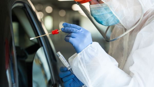 Medical NHS worker in personal protective equipment swabbing a person in a car drive through Coronavirus COVID-19 mobile testing center. (Shutterstock/ File Photo)