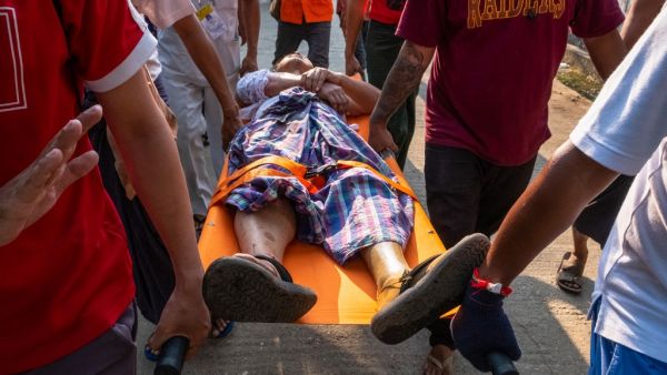 People carry an injured resident shot with rubber bullets 