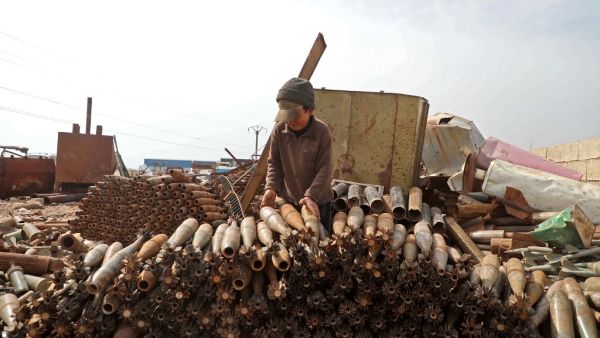 A Syrian child stacks neutralised mortar shells at a metal scrapyard on the outskirts of Maaret Misrin town in Idlib