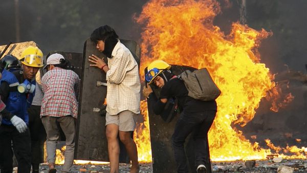 Protesters take cover behind homemade shields as they confront the police during a crackdown on demonstrations against the military coup in Yangon 